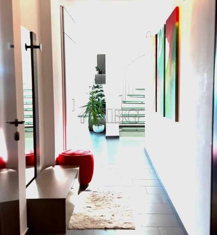 Bright hallway with colorful abstract paintings and a cozy red stool.