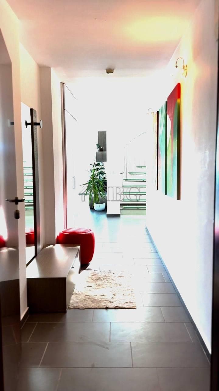 Bright hallway with colorful abstract paintings and a cozy red stool.