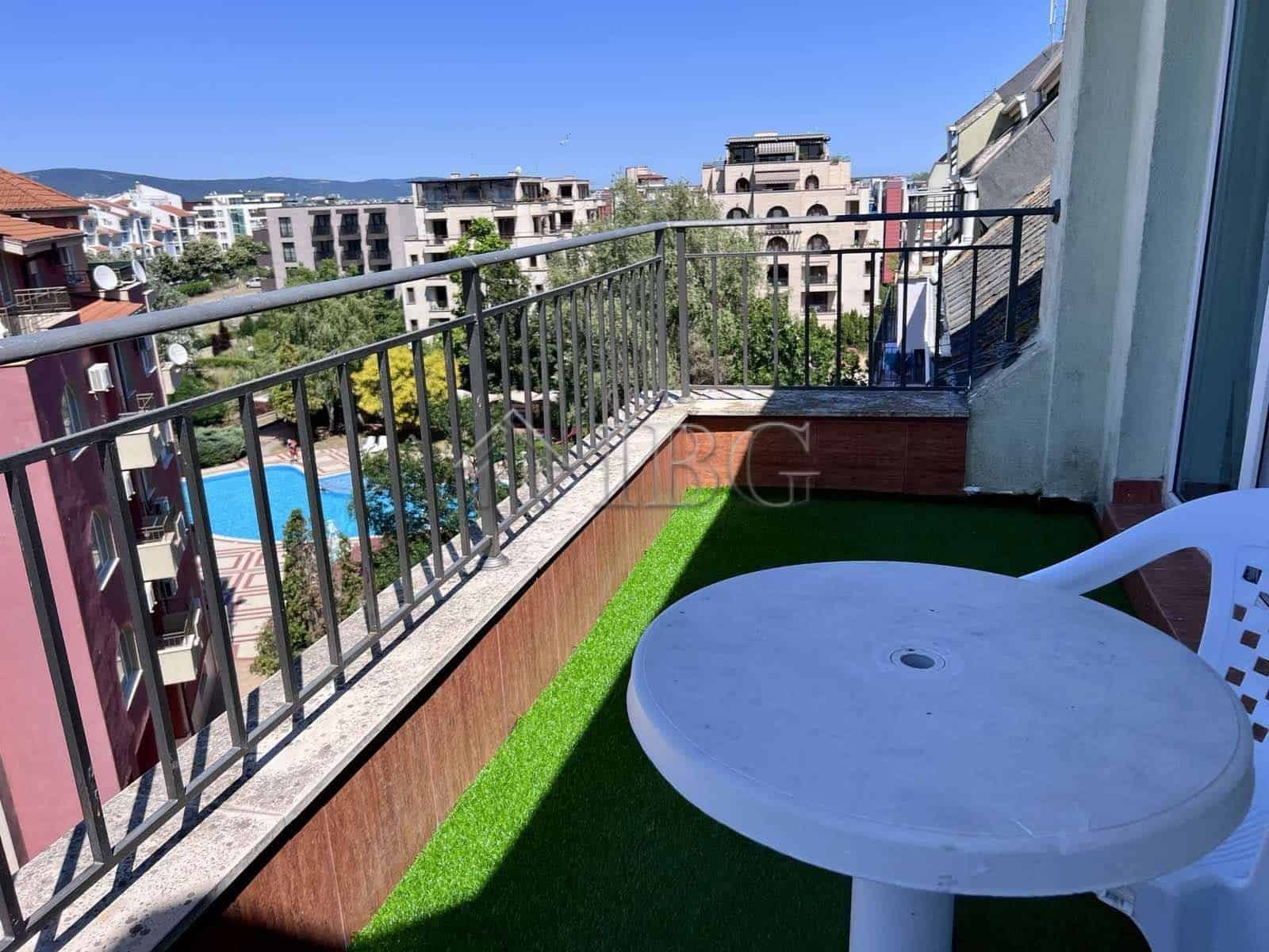 Balcony with pool view in Sveti Vlas apartment, featuring a small table and plastic chair.