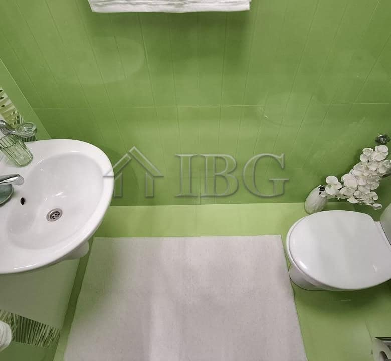 Bright green bathroom with sink and toilet in Nessebar apartment.