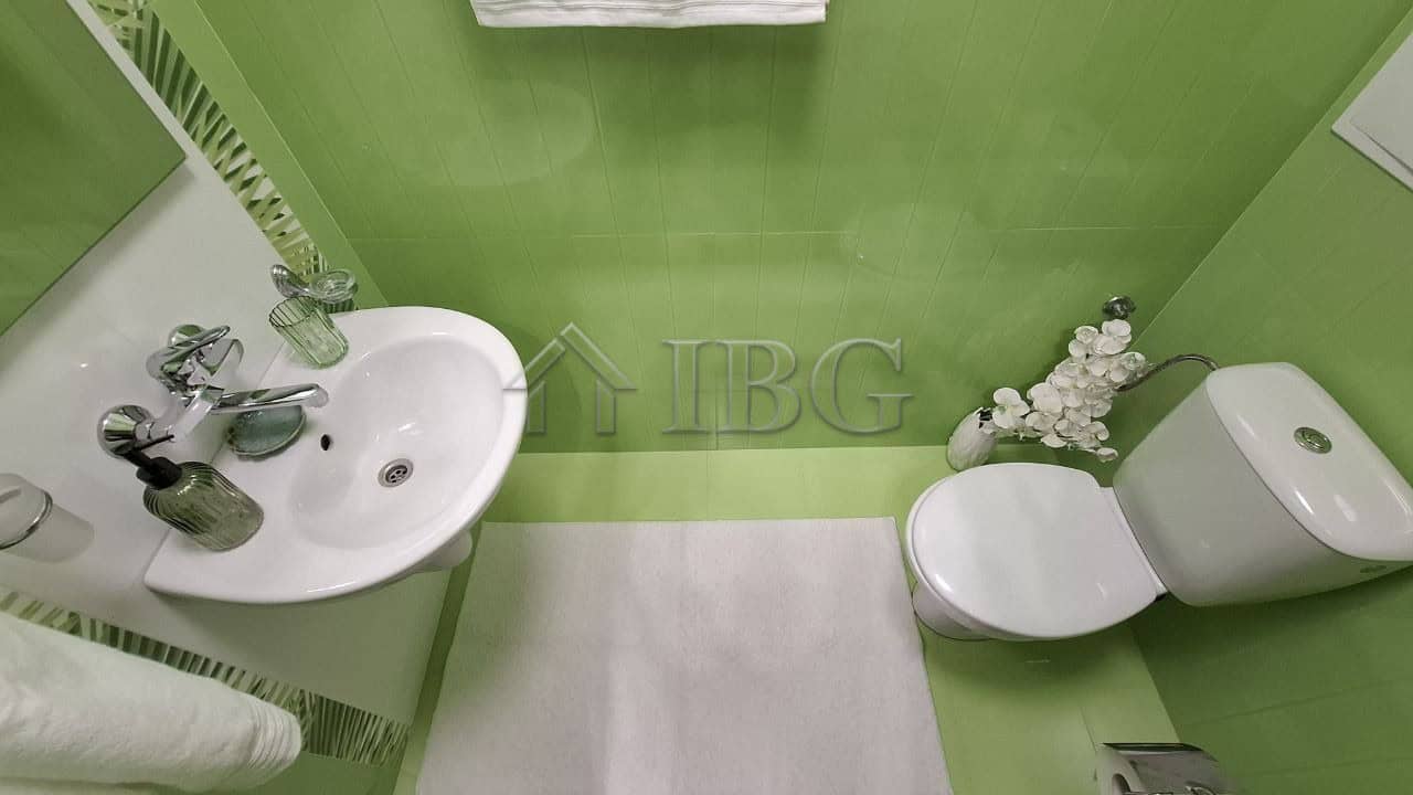 Bright green bathroom with sink and toilet in Nessebar apartment.