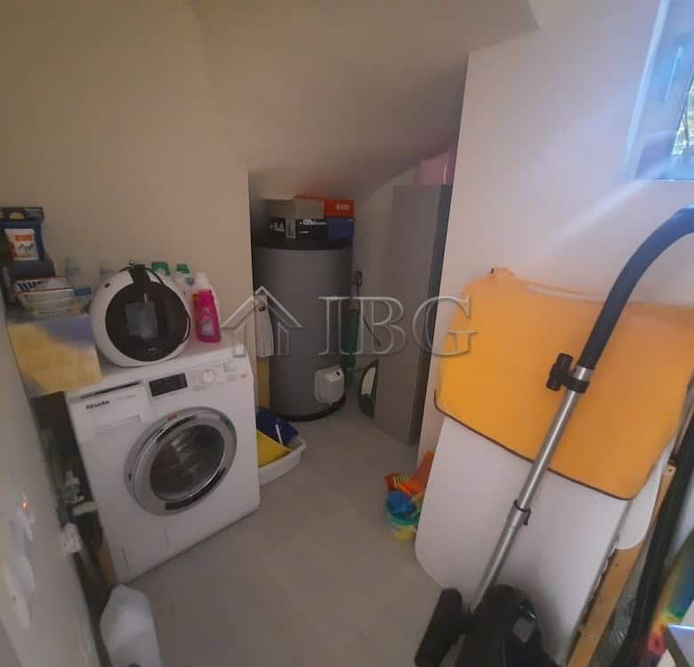 Laundry room with washing machine, cleaning supplies, and storage in a luxury townhouse.