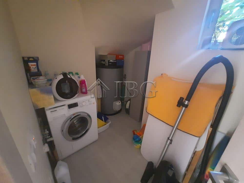 Laundry room with washing machine, cleaning supplies, and storage in a luxury townhouse.