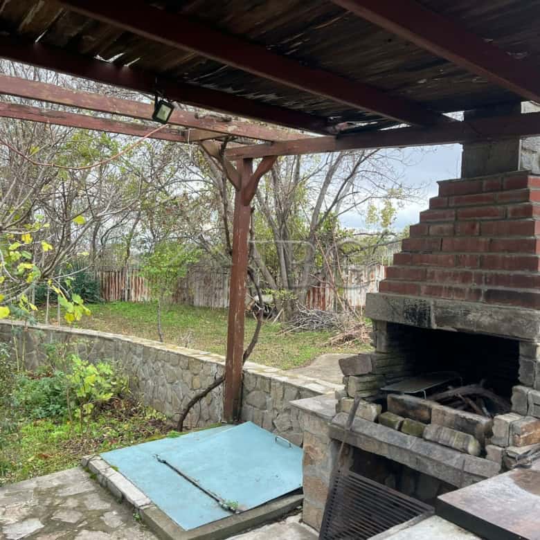 Outdoor brick barbecue with oven and shaded seating area.