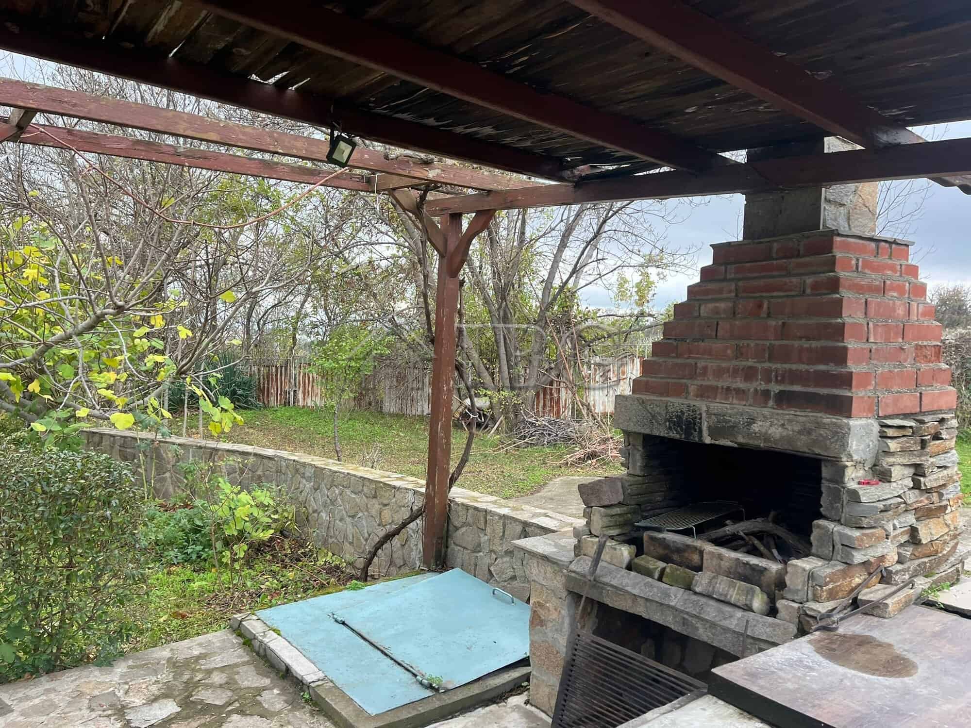 Outdoor brick barbecue with oven and shaded seating area.