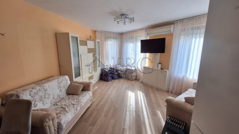 Bright living room of a 2-bedroom apartment in Ravda with large windows and modern furnishings.