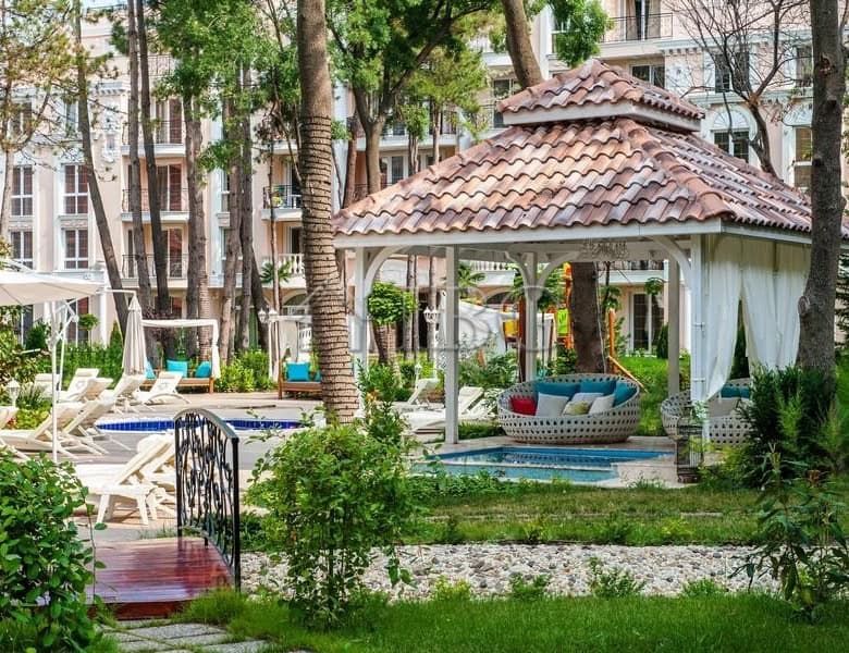 Beautiful outdoor pool area with lush greenery and a cozy gazebo at Venera Palace.