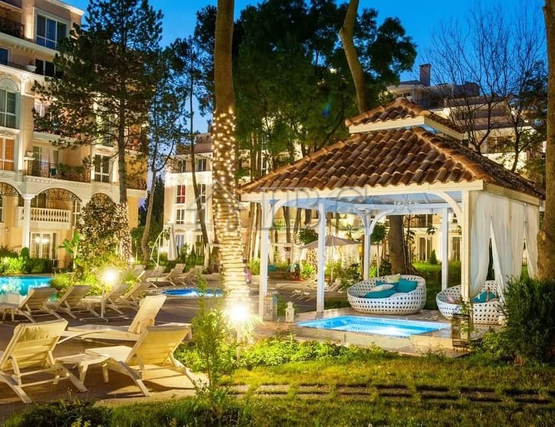 Beautiful outdoor pool area with lounge chairs and a cozy gazebo in a lush garden setting.