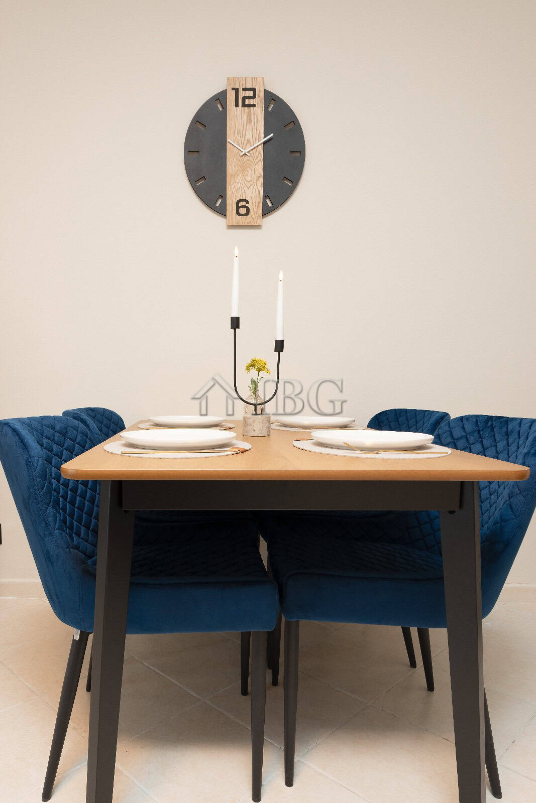 Stylish dining table set with blue velvet chairs and minimalist wall clock.