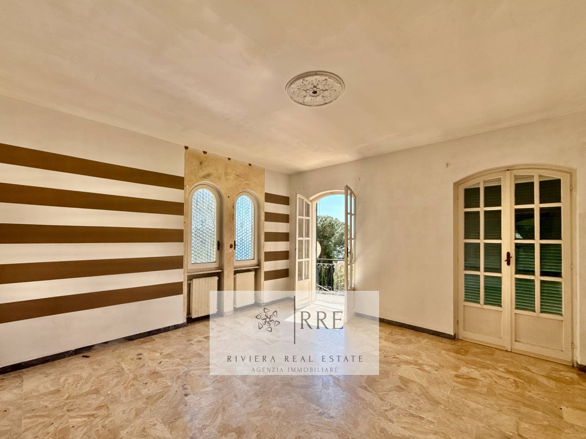 Bright living room with large windows and balcony access in a sunny property.