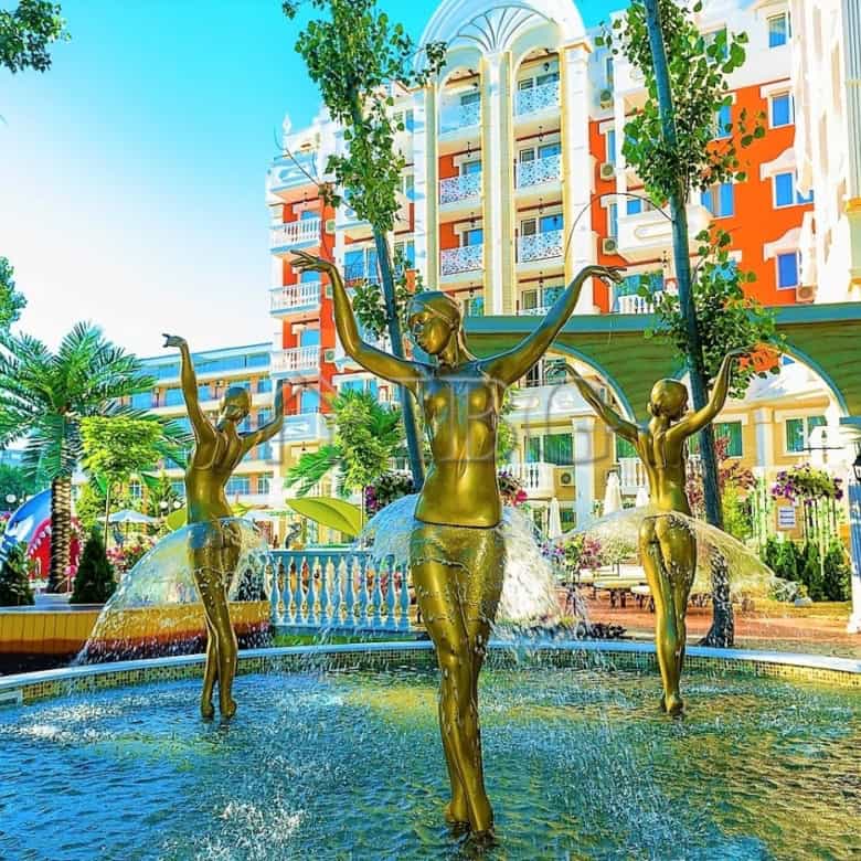 Beautiful fountain with golden statues in a sunny resort area.