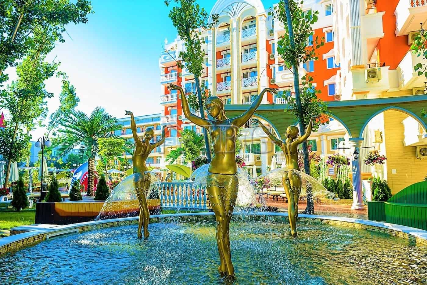 Beautiful fountain with golden statues in a sunny resort area.