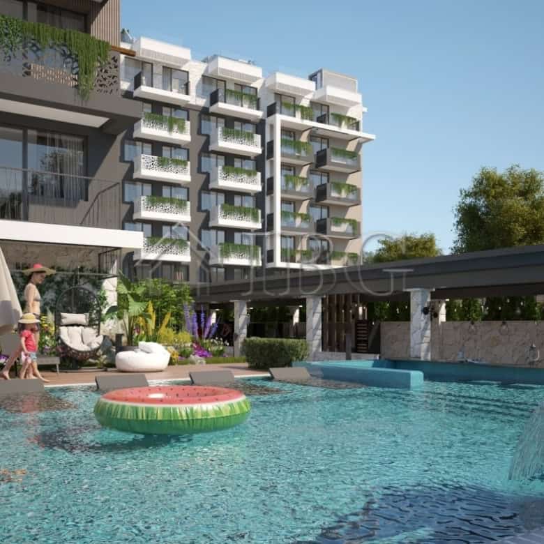 Contemporary apartment building with swimming pool and lush garden area in Sunny Beach.