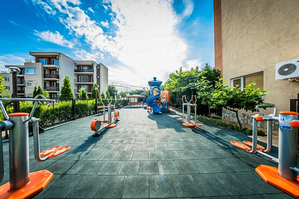Outdoor fitness area at Orchid Fort Club with pool view and exercise equipment.