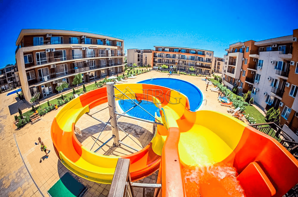 Bright pool view with water slides and surrounding residential buildings in Sunny Beach.