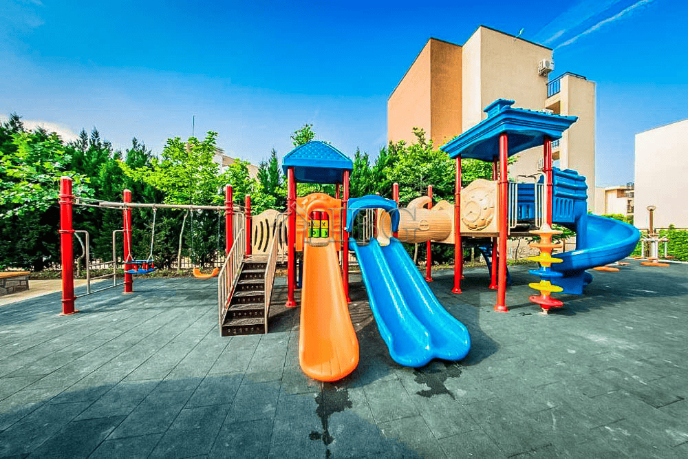 Bright outdoor playground at Orchid Fort Club with colorful slides and climbing structures.