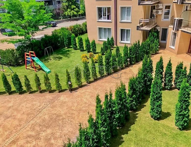 Bright apartment with balcony overlooking lush greenery and outdoor play space.