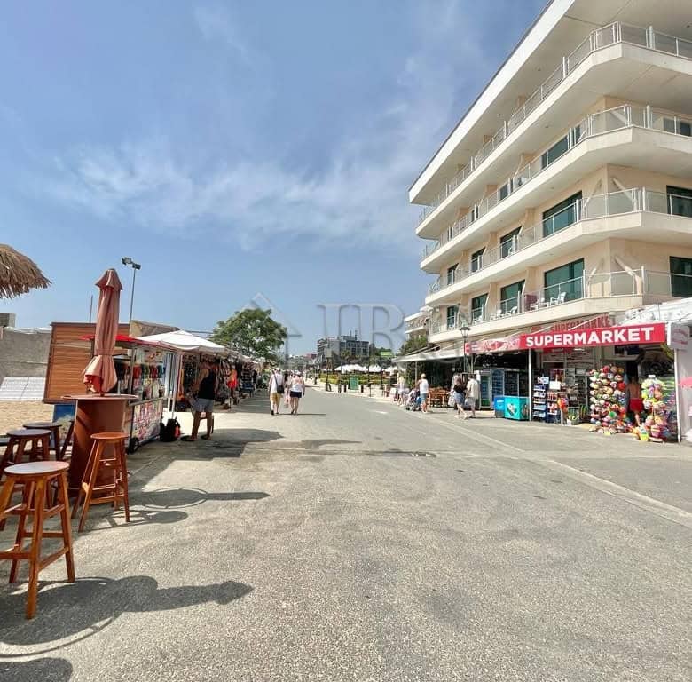 Beachfront summer building with shops and outdoor seating on sunny beach.