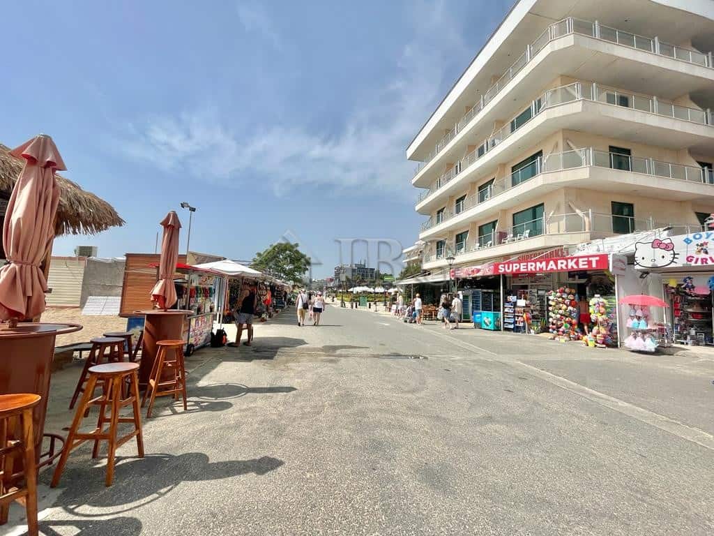 Beachfront summer building with shops and outdoor seating on sunny beach.
