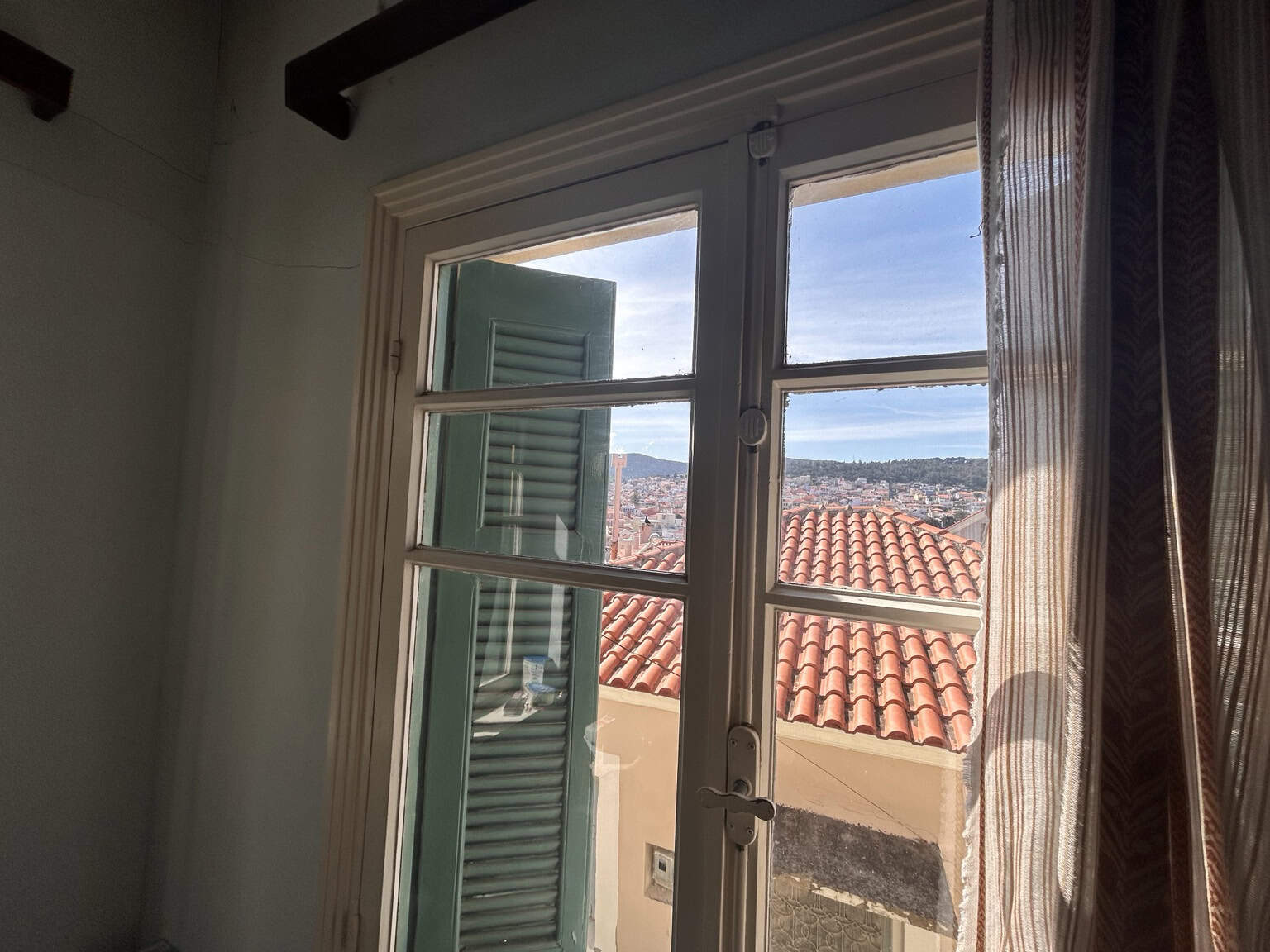 Cozy interior with a view of rooftops and the sea through a large window, showcasing Mediterranean a.