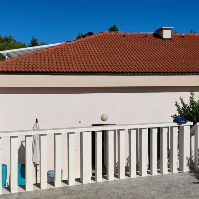 Bright apartment exterior with white balcony railing and lush greenery in Okrug Donji Croatia.