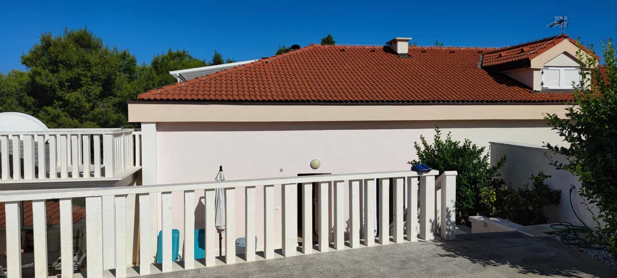 Bright apartment exterior with white balcony railing and lush greenery in Okrug Donji Croatia.