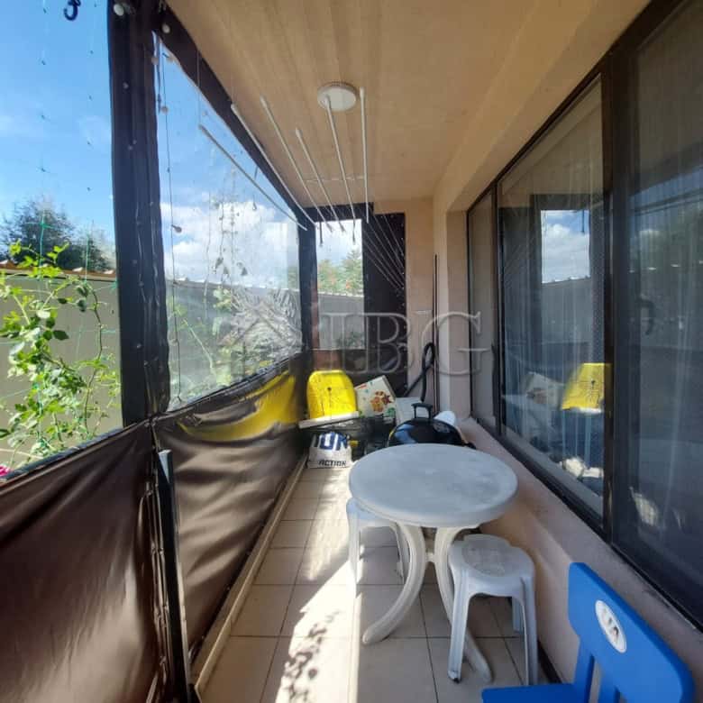 Bright balcony with outdoor seating and glass railing.