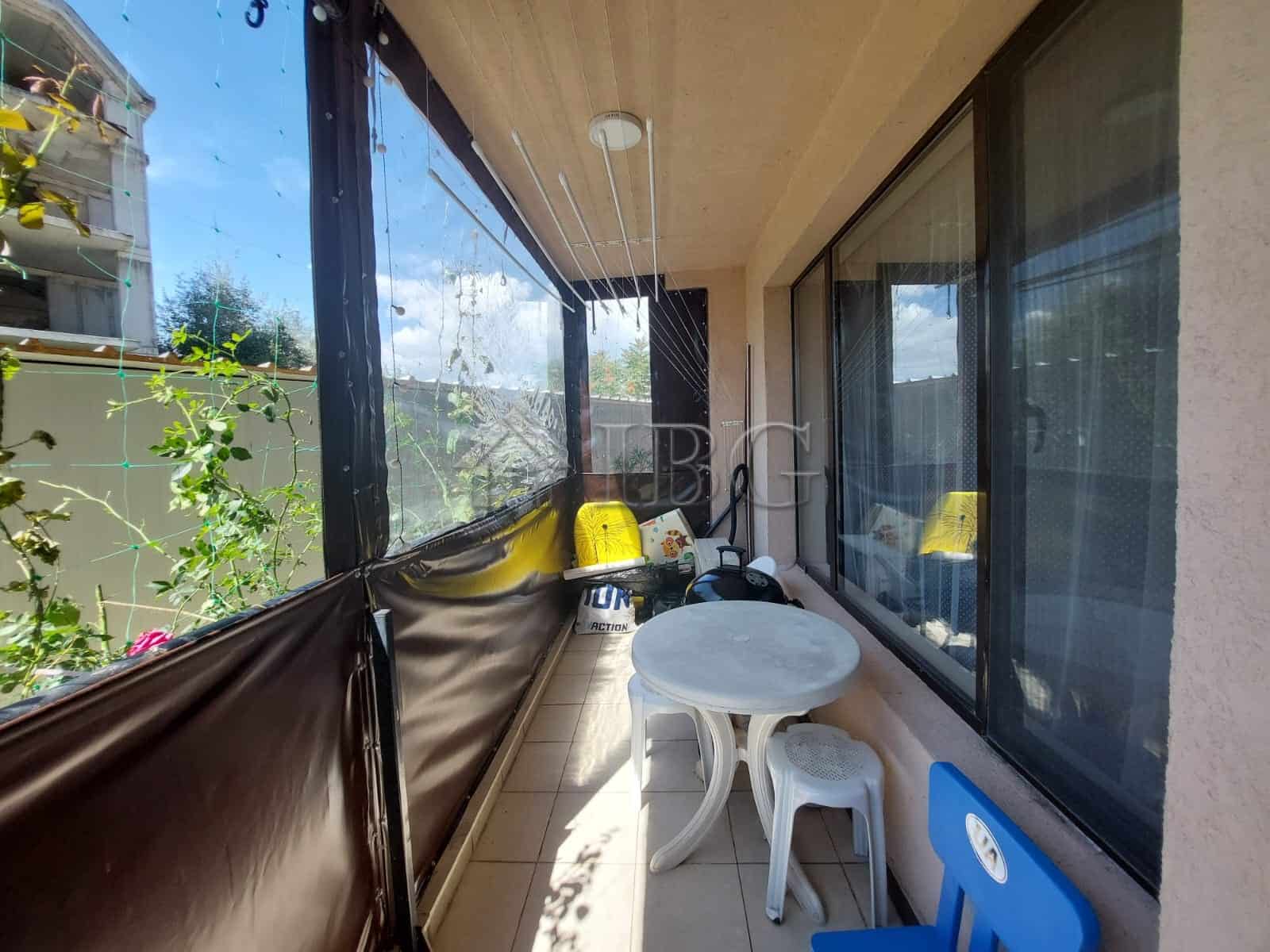 Bright balcony with outdoor seating and glass railing.