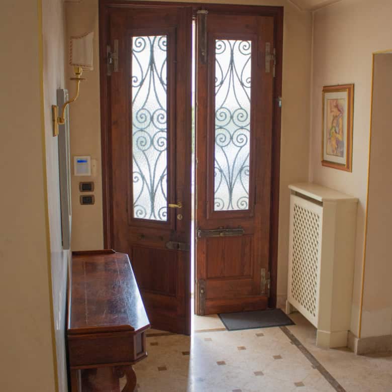 Front door with ornate iron grille, wooden frame, and glass panels.
