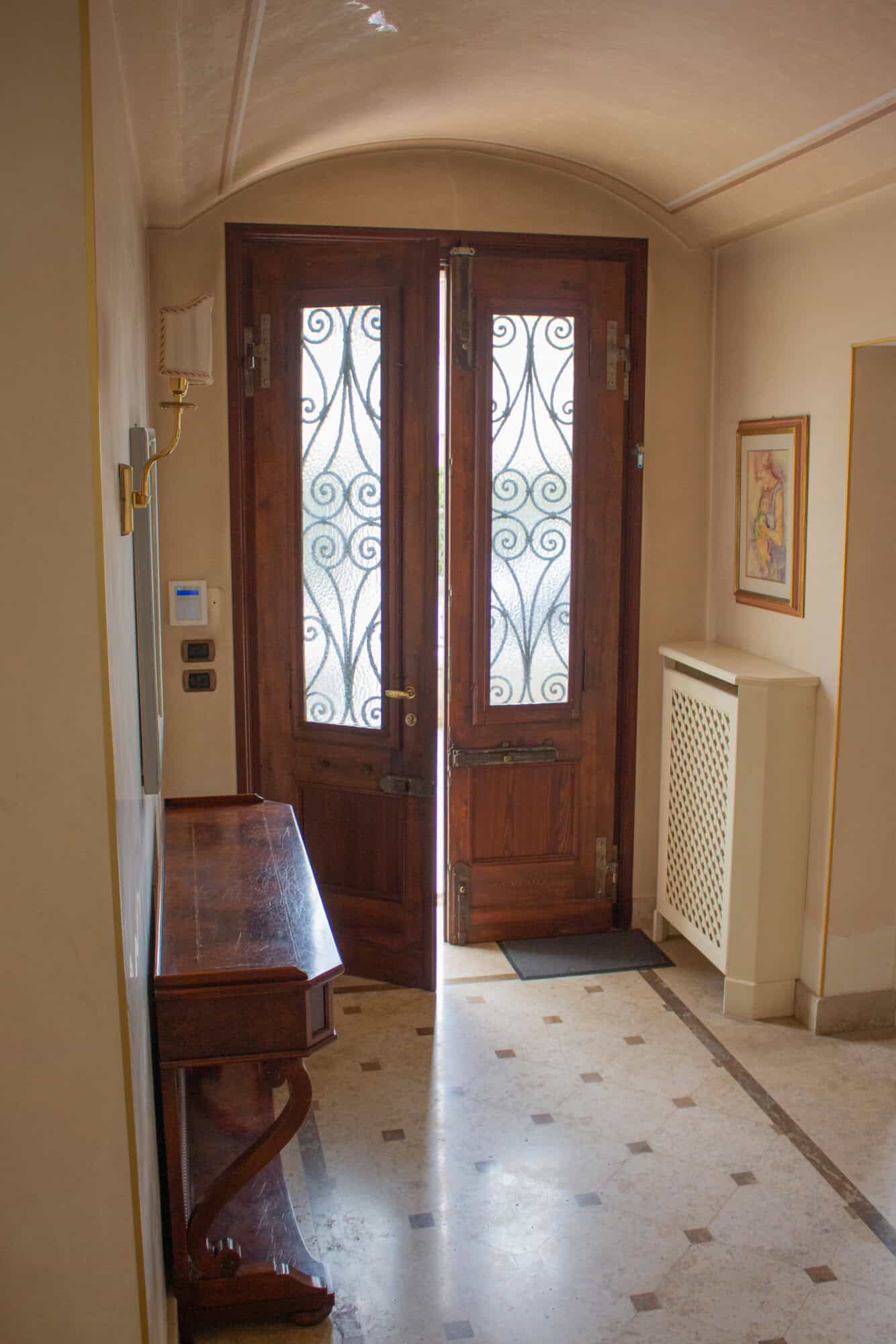 Front door with ornate iron grille, wooden frame, and glass panels.