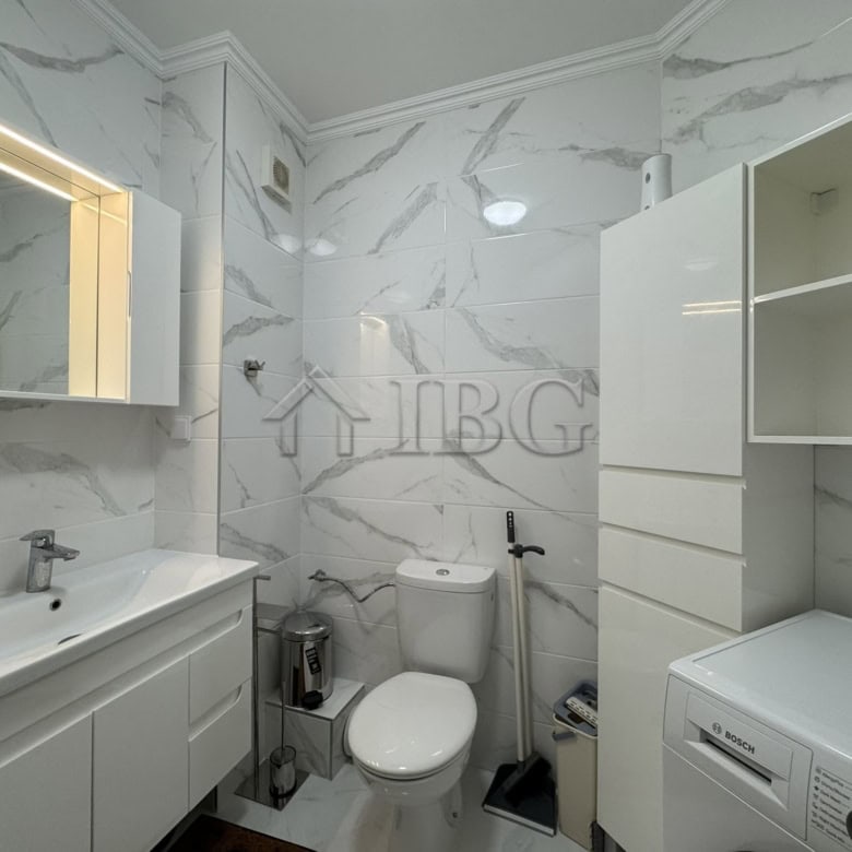Bathroom with double sink, toilet, and washing machine in a stylish apartment.