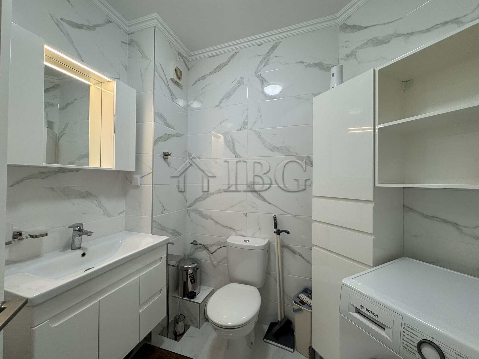 Bathroom with double sink, toilet, and washing machine in a stylish apartment.