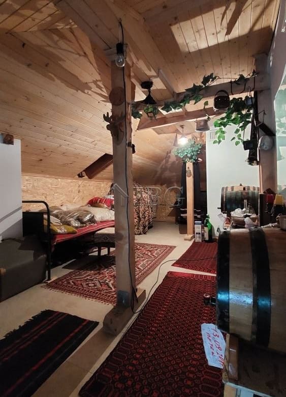 Attic space featuring wooden beams, cozy decor, and natural lighting in a family house in Burgas.