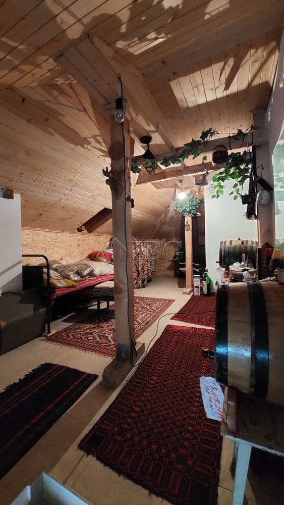 Attic space featuring wooden beams, cozy decor, and natural lighting in a family house in Burgas.