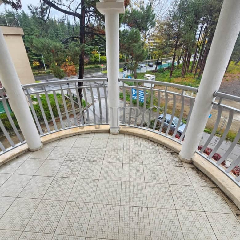 Apartment with balcony overlooking pool and greenery.