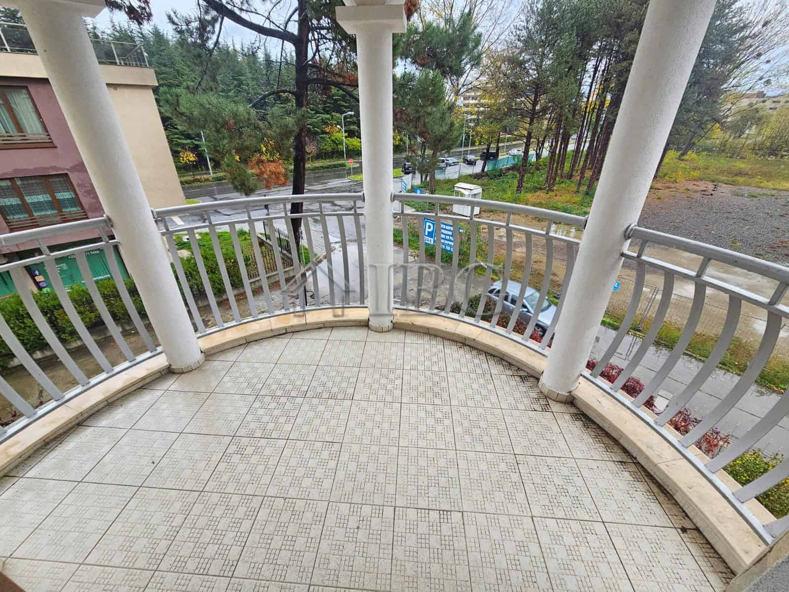 Apartment with balcony overlooking pool and greenery.