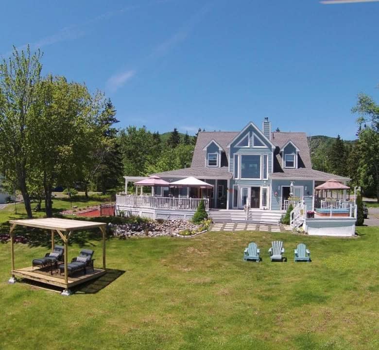 Ocean view manor in Englishtown, Nova Scotia, with spacious lawn and scenic surroundings.