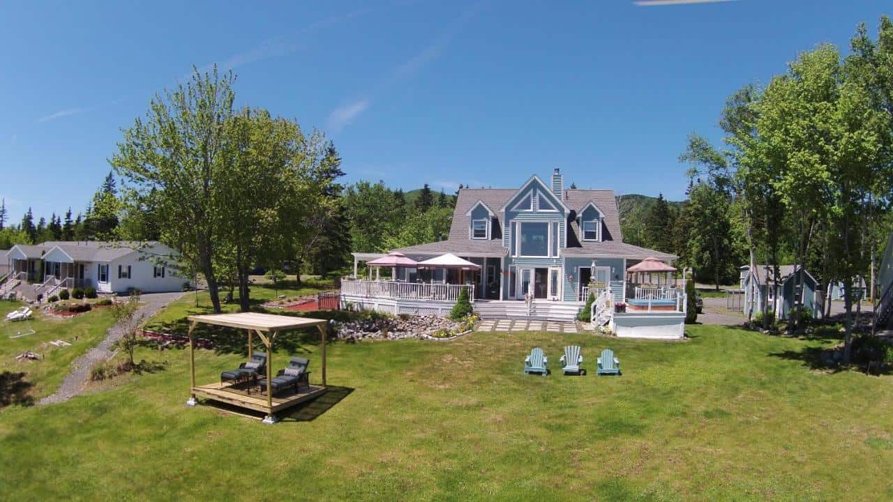 Ocean view manor in Englishtown, Nova Scotia, with spacious lawn and scenic surroundings.