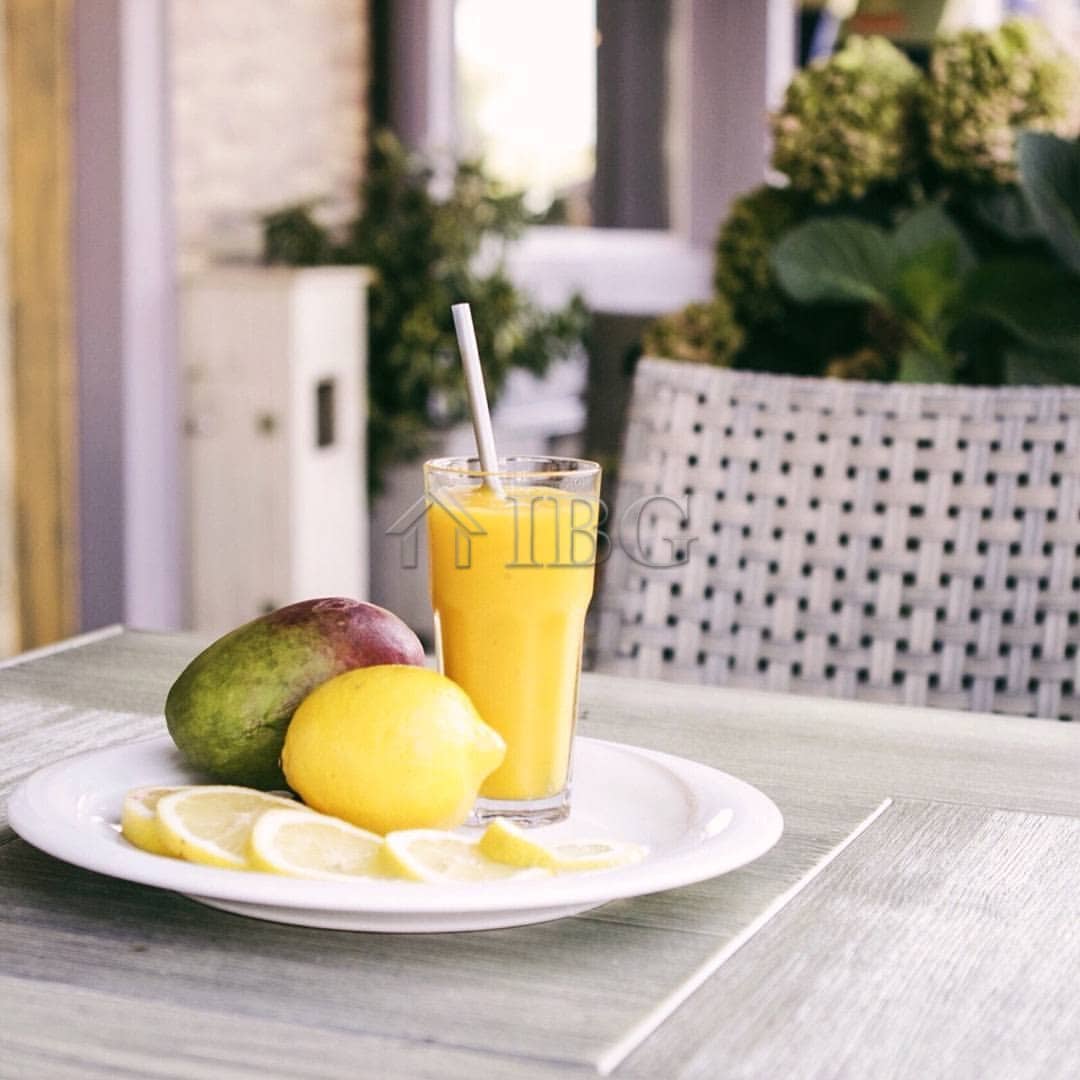 Fresh lemonade served with mango and lemon slices on a table at an outdoor restaurant.