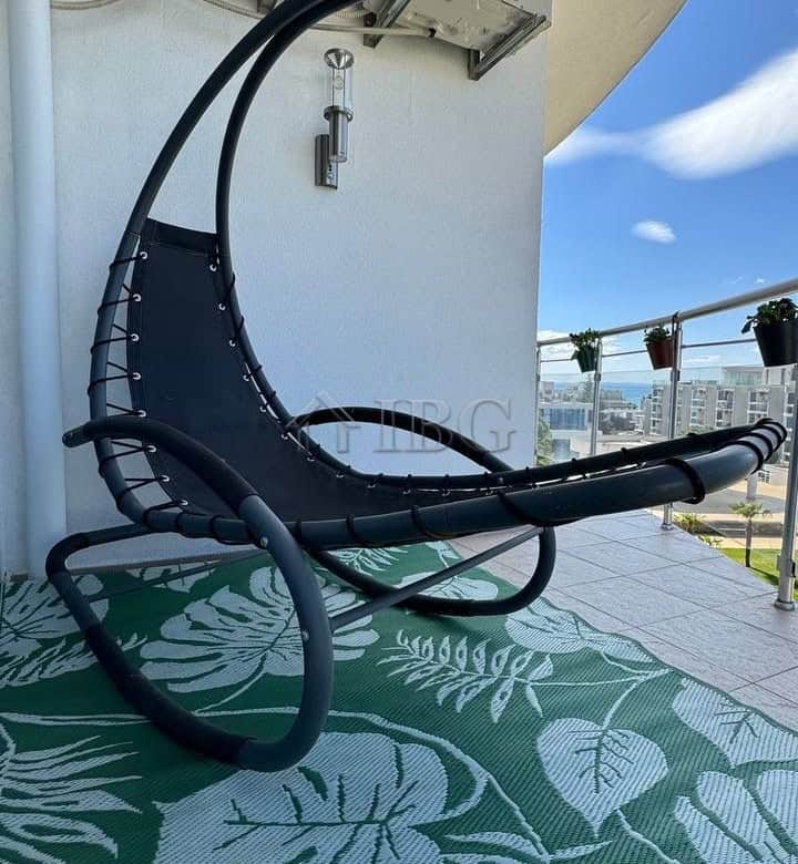 Balcony with sea and pool views, featuring air conditioning units and a modern lounge chair for rela.