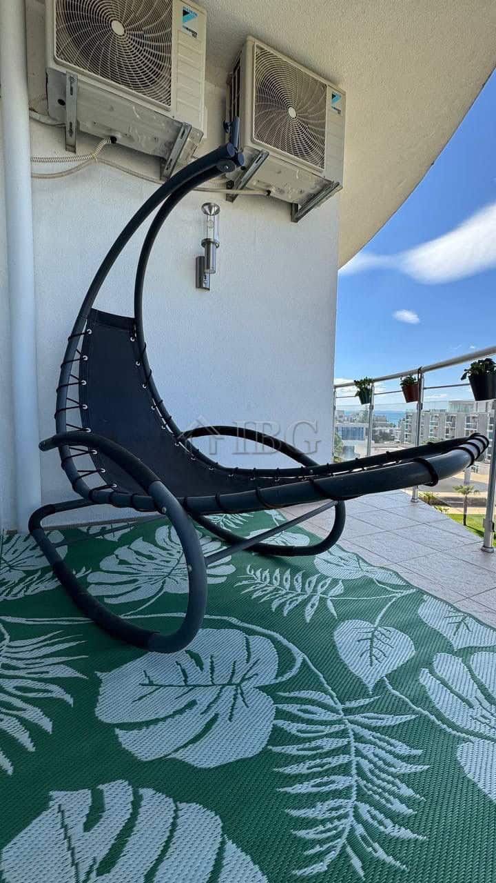 Balcony with sea and pool views, featuring air conditioning units and a modern lounge chair for rela.