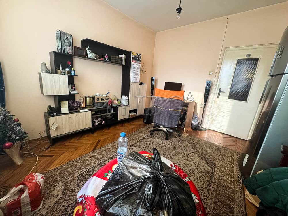 Spacious living room with furniture, shelves, and personal items in a central Ruse location.