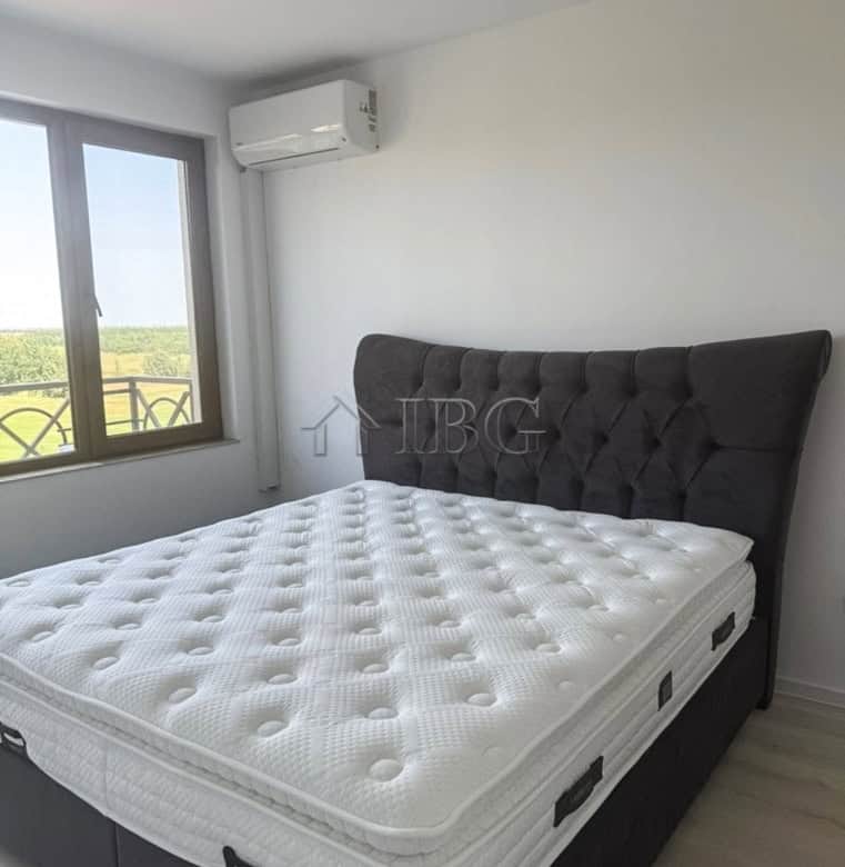 Modern bedroom with large window overlooking golf course.