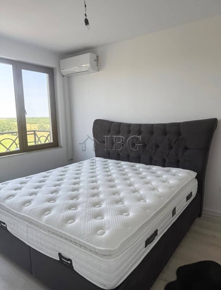 Modern bedroom with large window overlooking golf course.
