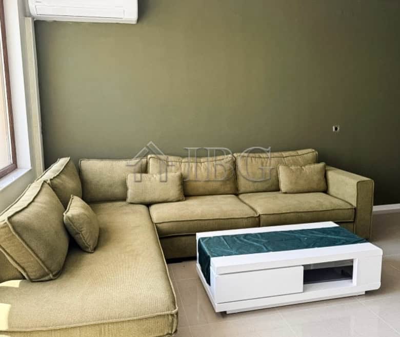 Comfortable living room with a large beige sofa and scenic golf views from the window.