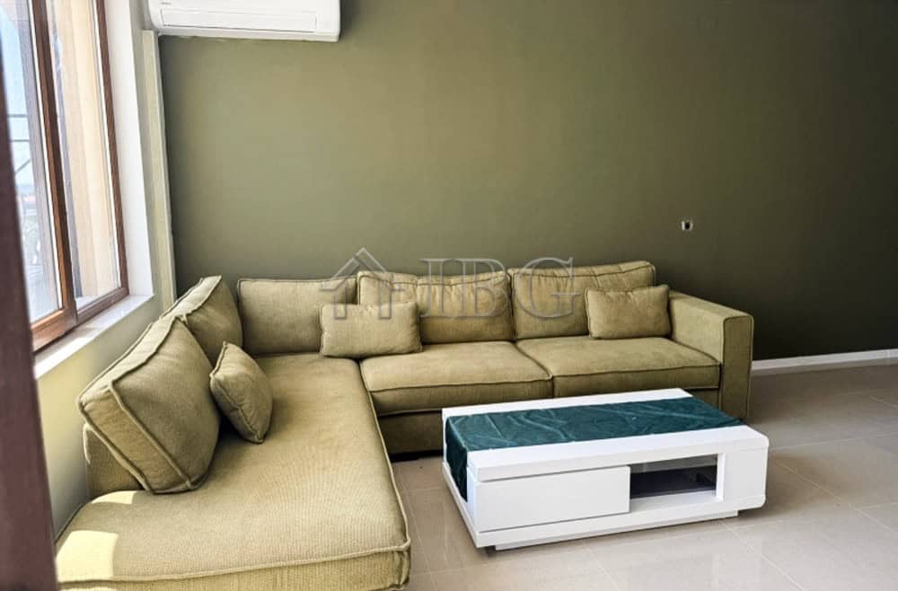 Comfortable living room with a large beige sofa and scenic golf views from the window.