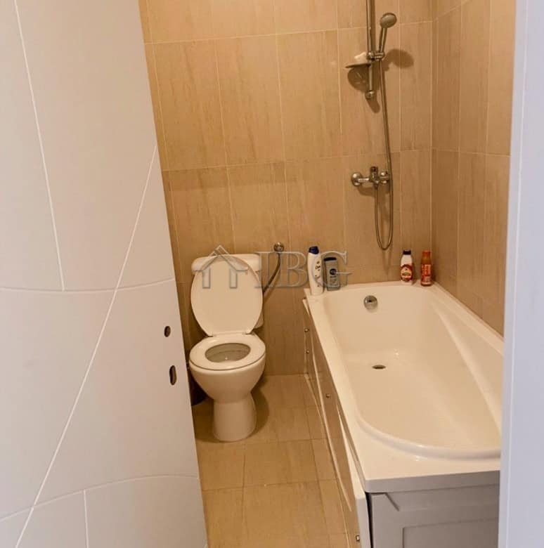 Bright bathroom featuring a bathtub, shower, and toilet in a contemporary apartment.