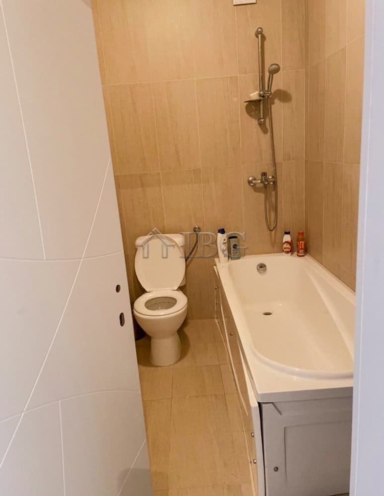 Bright bathroom featuring a bathtub, shower, and toilet in a contemporary apartment.
