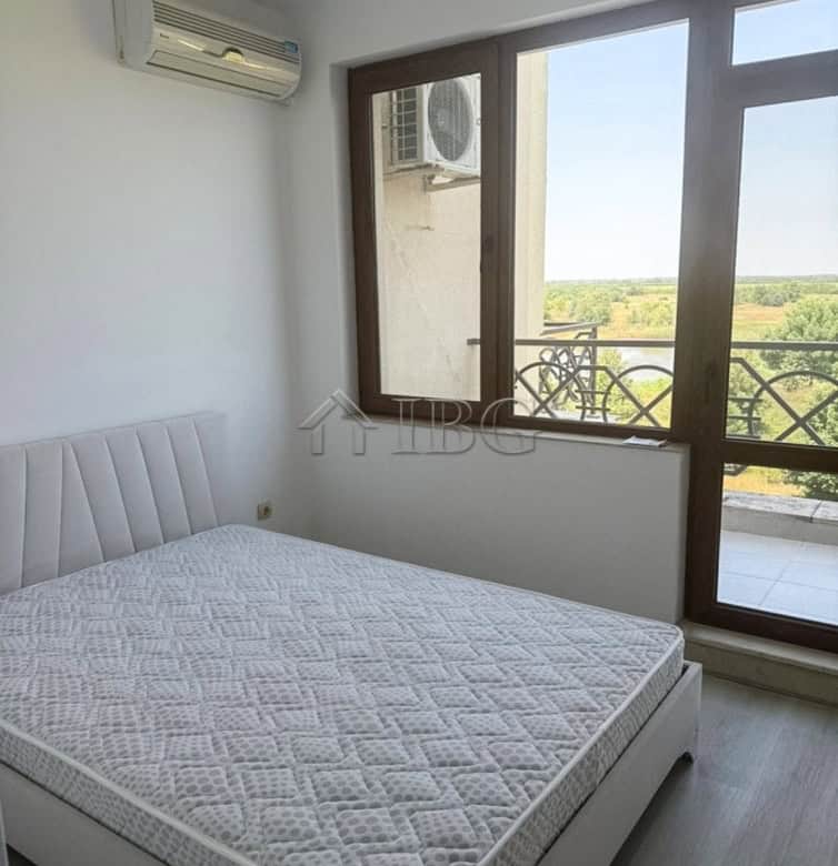 Spacious bedroom with large windows and balcony offering scenic golf views.