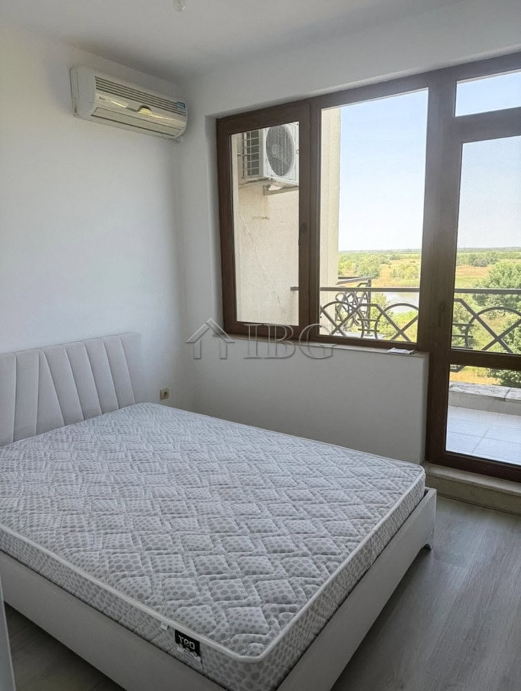 Spacious bedroom with large windows and balcony offering scenic golf views.